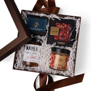 Felülnézeti termékfotó prémium ajándékcsomagról barna díszdobozban, kézműves lekvárral, csokoládéval és gourmet finomságokkal.