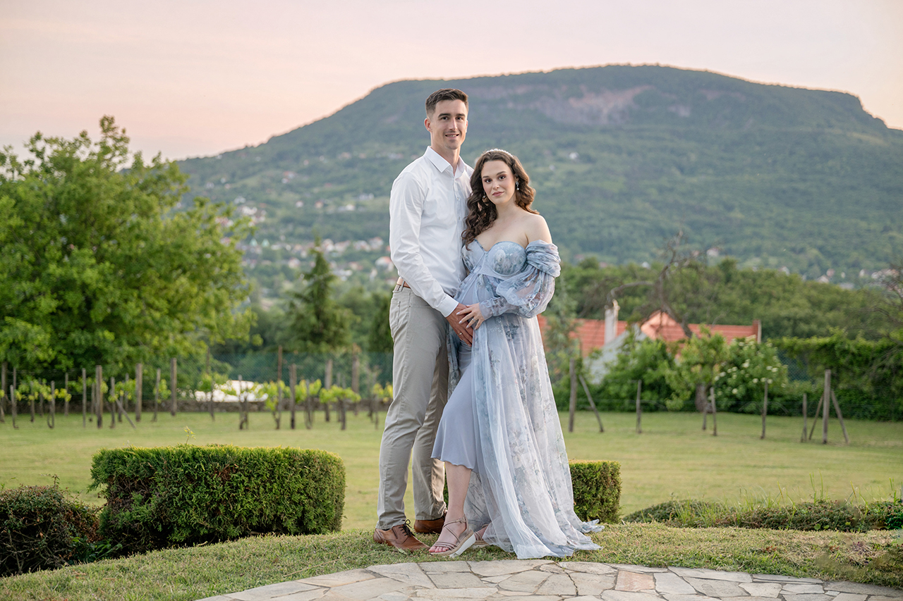 Kismama és párja romantikus portrén a Badacsony hegyével a háttérben egy balatoni kismama fotózáson.